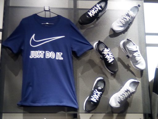 T-shirt bleu avec le slogan "JUST DO IT." et plusieurs chaussures de sport noires et grises.